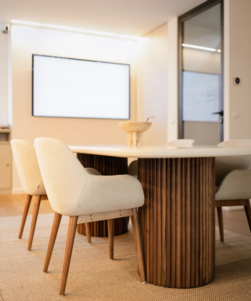 Mesa de reuniões com cadeiras beje e ecrã de visualização num estúdio fotográfico bebê.